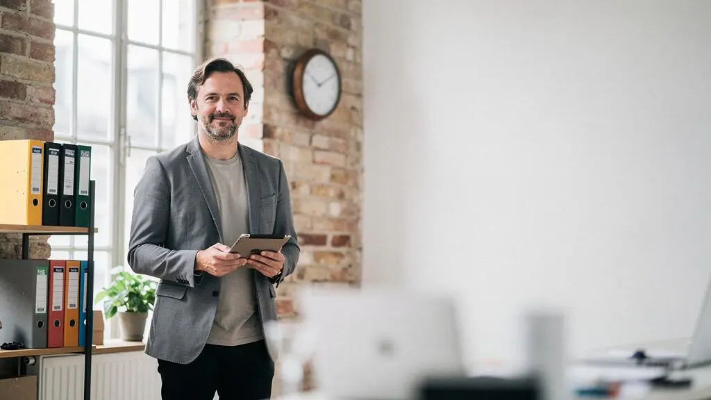 Dirigeant de PME française organisant sereinement sa communication digitale depuis un bureau lumineux et épuré